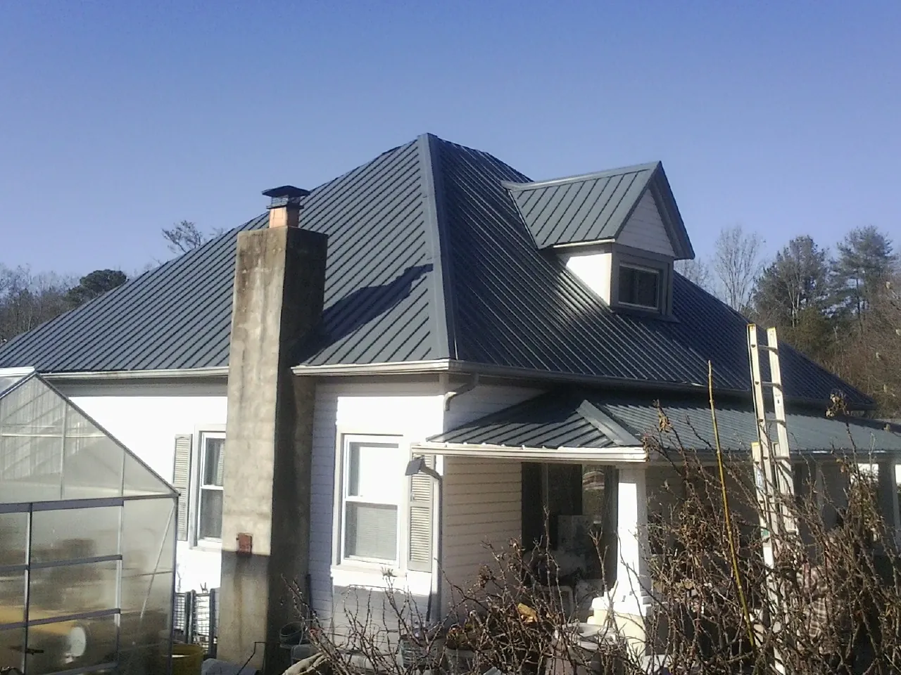 Dark blue standing seam metal roof on a white farmhouse with dormer — Slate & Tile Roof Repair by Roofing Brothers in Bird In Hand