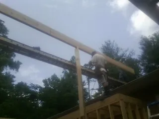 Carpenter setting a ridge beam over a new addition frame — Ice Dam Removal by Roofing Brothers in Bird In Hand