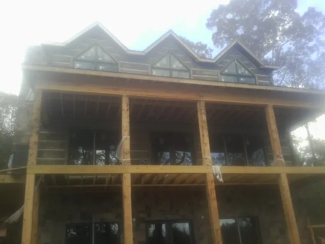 Dormers and porch framing on a large log home under construction — Roof Coating work by our crew in Bird In Hand