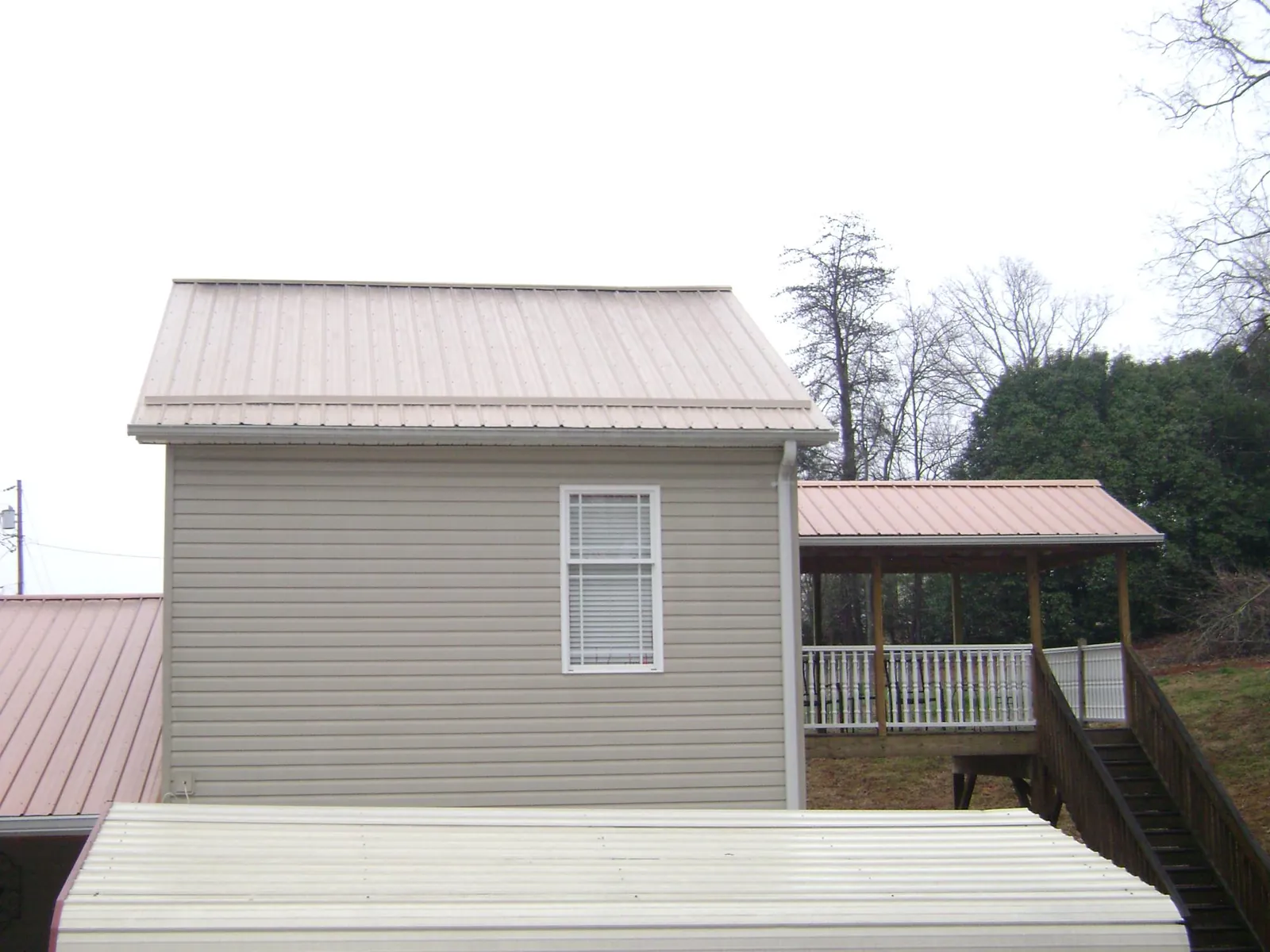 Tan metal roofs on a two story addition and attached porch, from a Roof Replacement job in Bird In Hand