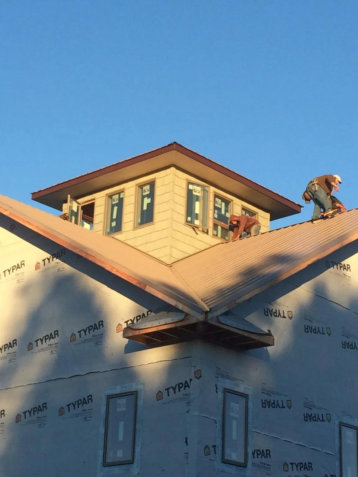 Roofers working around a rooftop cupola on a new metal roof at sunset — Roof Waterproofing in Bird In Hand by Roofing Brothers